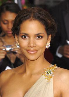 a close up of a person wearing a dress and smiling at the camera with other people in the background