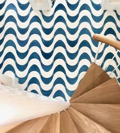 a wooden staircase in front of a blue and white wall with wavy waves on it