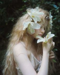 a woman with long blonde hair and flowers in her hair is posing for the camera