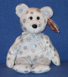 a white teddy bear with snowflakes on it's face and ears, sitting in front of a blue background