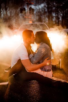 Smoke and golden light from a car lights up a couple. They are sitting on the ground in each other arms. She pulls him in and they are about to kiss. Engagement Photoshoot With Car, Bronco Couples Shoot, Car Lights Photoshoot, Engagement Pictures With Car, Couples Photoshoot Car, Couple Creative Photography, Engagement Photos Unique Creative, Car Light Photoshoot, Photo Ideas With Car