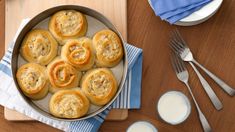 a pan filled with food on top of a wooden table next to utensils