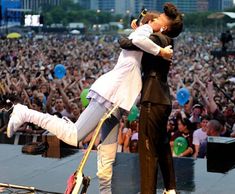 a man and woman hugging on stage in front of an audience at a music festival