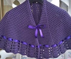 a purple crocheted shawl hanging on a rack