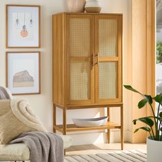 a wooden cabinet sitting in the corner of a room next to a chair and potted plant