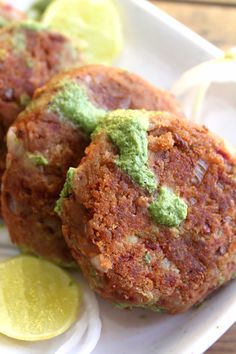 three crab cakes on a white plate with lemon wedges next to it and a lime slice