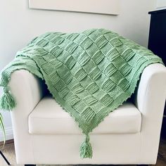 a white chair with a green blanket on it