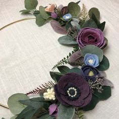 an arrangement of flowers and greenery on a white tablecloth with a circular frame