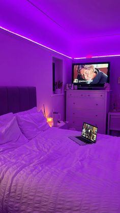 a laptop computer sitting on top of a bed in a room with purple walls and furniture