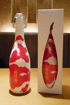 a red and white bottle with clouds on it next to a box for the sake