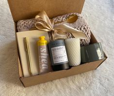 an open box with some items in it on a white carpeted floor next to a gold ribbon