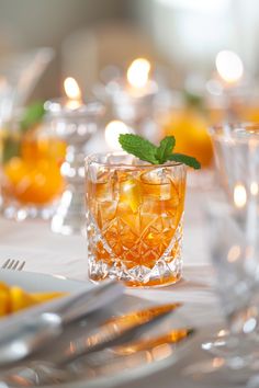 a table topped with glasses and silverware filled with oranges, lemons and mint