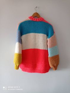 a multicolored sweater hanging on a white wall