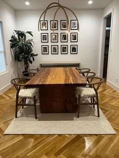 a dining room table and chairs in front of pictures on the wall above it, with wood flooring