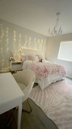 a bedroom decorated in pink and white with lights on the wall above the bed, along with a desk and chair