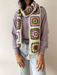 a woman is wearing a crocheted scarf with flowers and fringes on it