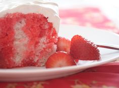 a piece of red velvet cake with white frosting and strawberries on a plate