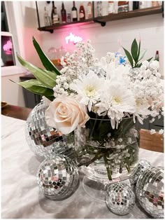 a vase filled with white flowers sitting on top of a table next to disco balls