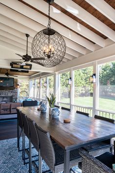 a large wooden table sitting under a light fixture in a room with lots of windows