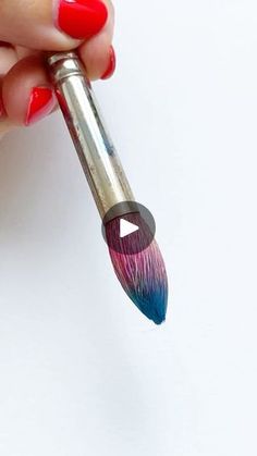 a woman's hand holding a paintbrush with red and blue streaks on it