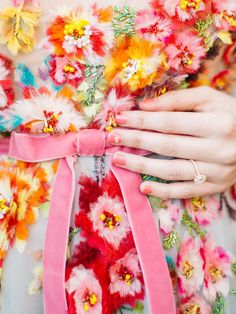 a close up of a person's hands with flowers on their dress and pink ribbon