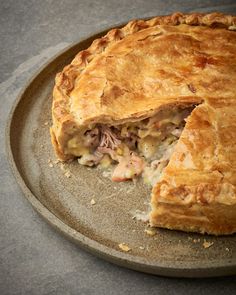 a meat and vegetable pie on a plate with one slice missing from it's crust