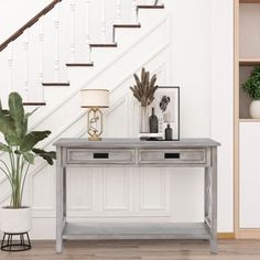 a table with two drawers and a lamp next to it in front of a stair case