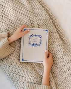 a person is laying on a bed with a book in their hand and holding it up