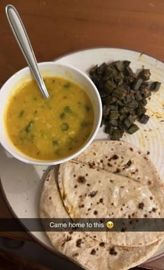 a white plate topped with food next to a bowl of soup and tortilla