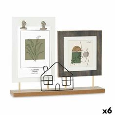 two framed pictures are sitting next to each other on a wooden stand, one has a house and the other is a bird