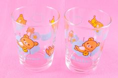 two glasses with cartoon animals on them sitting next to each other in front of a pink background