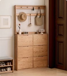 a wooden dresser sitting next to a wall with hats hanging on it's hooks