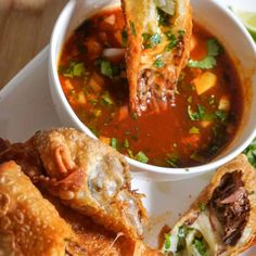 a white plate topped with food next to a bowl of soup