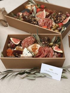 two boxes filled with assorted meats and vegetables on top of a white table