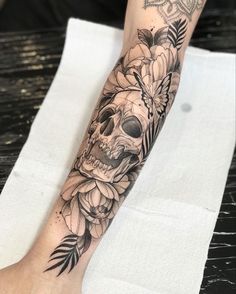 a person with a tattoo on their arm has a skull and flowers tattooed on it