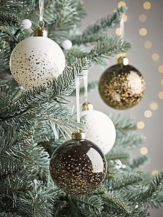 three ornaments hanging from the top of a christmas tree with gold and white decorations on it