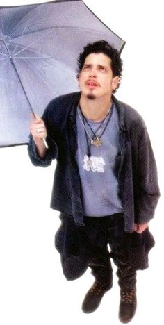 a young man is holding an umbrella and posing for the camera while standing in front of a white background