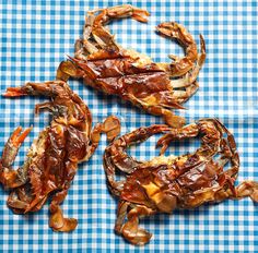 three cooked crabs on a blue and white checkered tablecloth