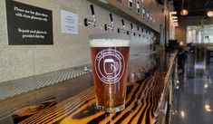 a pint of beer sitting on top of a wooden table next to a bar