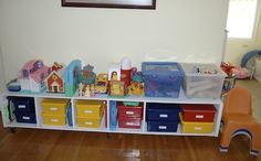 a room filled with lots of toys on top of a white shelf next to a window