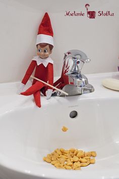 an elf is sitting in the bathroom sink with food on the counter next to it