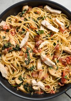 pasta with chicken, spinach and tomatoes in a skillet