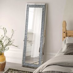 a bedroom with a bed and a large mirror on the wall next to a plant