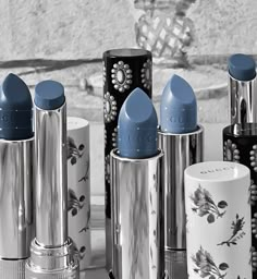 many different types of lipsticks are lined up on a table with one blue and the other black