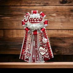 a red and white ribbon with the word jacob on it is sitting on a shelf