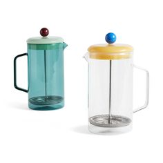 two glass teapots one with a yellow lid and the other blue