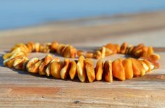 a close up of a necklace on a wooden surface with water in the back ground