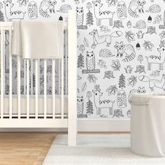 a white crib in front of a wall with black and white animals on it