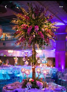 a tall centerpiece with purple flowers and hanging glass globes is the focal point for this elegant wedding reception