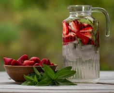 strawberries and mint in a glass pitcher on a table